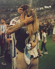 two people embracing each other in front of an audience at a soccer game with fans behind them