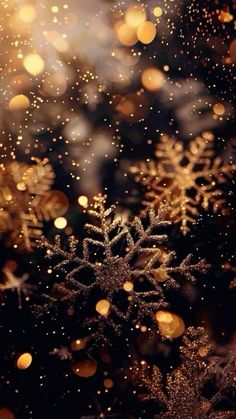 snowflakes are shining in the dark and blurry background with gold glitters