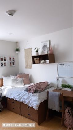 a bedroom with a bed, desk and hanging plants on the wall next to it