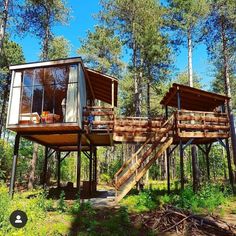 two cabins in the woods with stairs leading up to them and windows on each side