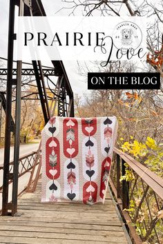 a blanket sitting on top of a wooden bridge with the words prairie love on it