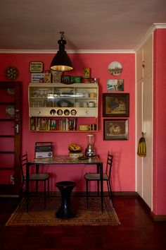 a dining room with pink walls and wooden floors