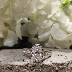 a diamond ring sitting on top of a rock next to white flowers and greenery