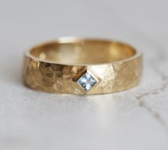 a gold wedding band with a blue diamond in the center