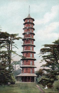 a tall red tower sitting in the middle of a lush green field next to trees