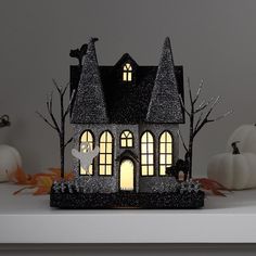 a lighted house with bats and pumpkins in the background