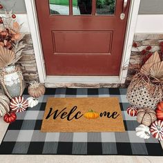 a welcome mat on the front door with candy canes and pumpkins around it