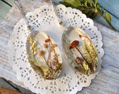 two necklaces with dried flowers on them sitting on a doily