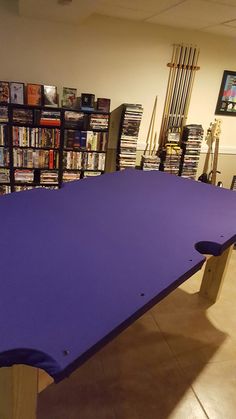 a large purple table sitting in front of a book shelf filled with books and video games