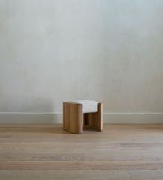 an empty room with wooden flooring and a white chair in the corner on one side