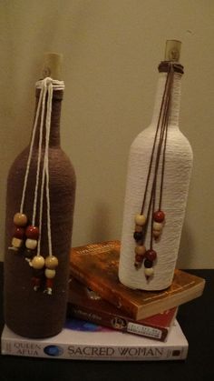 two vases sitting on top of a table next to each other with beads hanging from them