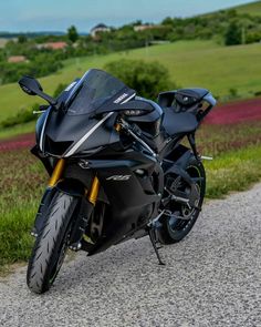 a black motorcycle parked on the side of a road next to a lush green field