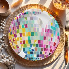 a colorful mosaic plate sitting on top of a table next to candles and other items