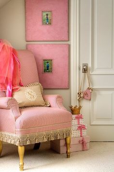 a pink chair sitting in front of a wall with pictures hanging on it's side