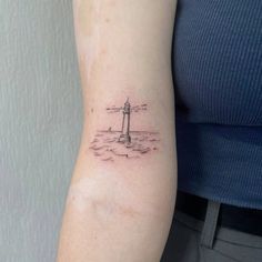 a small lighthouse tattoo on the arm