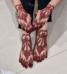 the legs and feet of a woman with henna tattoos on their hands, both covered in red beads