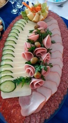 a platter with cucumbers, olives and ham