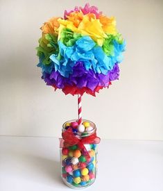 a candy jar filled with colorful candies on top of a white table next to a wall