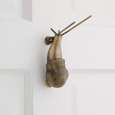 a metal object hanging from the side of a white door with two wooden sticks sticking out of it