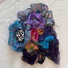 an assortment of scarves and hair clips on top of a white sheeted surface