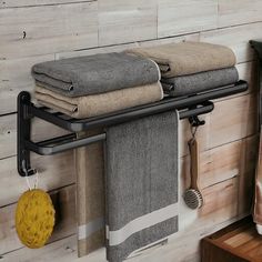 towels are hanging on a towel rack in a bathroom with wood paneled walls and wooden flooring