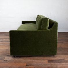 a green couch sitting on top of a wooden floor