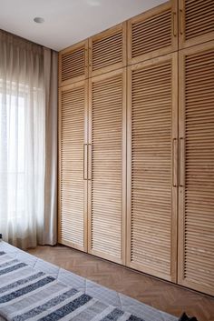 an empty bedroom with wooden closets and curtains