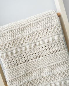 a white crocheted blanket hanging from a wooden frame