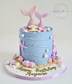 a blue cake with pink and white decorations on it's sides, under the sea