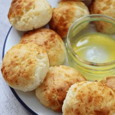 some biscuits are sitting on a plate next to a small jar of olive oil,