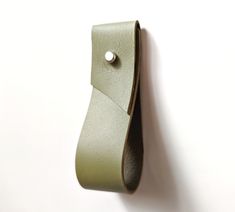 a leather wallet hanging on a wall with a button in the middle and two holes at the bottom