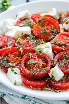 tomatoes, mozzarella and basil on a white platter ready to be eaten