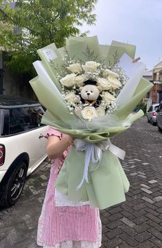 a woman holding a bouquet of flowers with a teddy bear on it