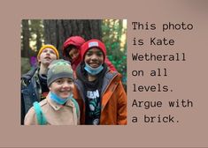 there are four children standing together in the woods, one is wearing a hat and the other has a jacket