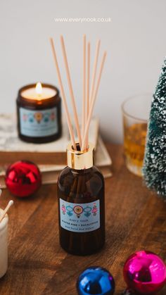 a bottle with some sticks in it sitting on a table next to christmas decorations and candles