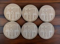 four wooden coasters with the emblem of several different teams on them, sitting on a wood surface