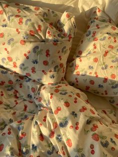 an unmade bed with white sheets and red flowers