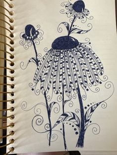 a drawing of a flower with swirls and leaves on it's side, in front of a spiral notebook