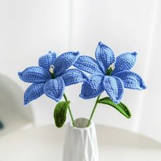 three crocheted blue flowers in a white vase