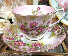 a cup and saucer sitting on top of a table next to other plates with flowers painted on them