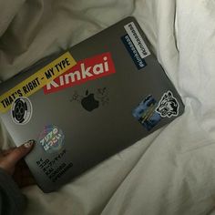 a person is holding an apple laptop with stickers on the cover and it's right - my - type, kmokii