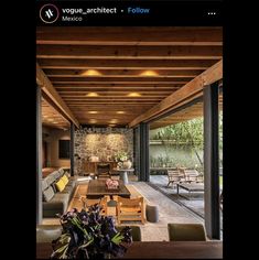 a living room filled with furniture and a stone wall next to a wooden table covered in flowers