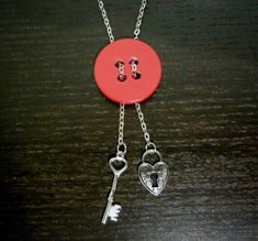 a red button with two keys attached to it on a chain that is sitting on a table