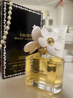 a bottle of marc jacoti daisy perfume next to a box with pearls on it