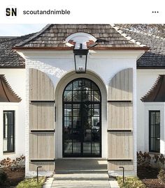 the front entrance to a white building with black shutters and arched glass doors on both sides