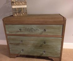 a green dresser with two drawers and a birdhouse on top