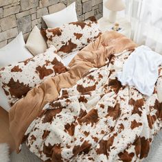 a bed covered in brown and white cow print blankets