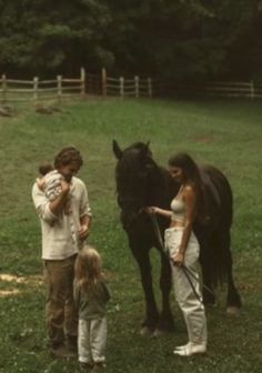 a man, woman and child standing next to a black horse