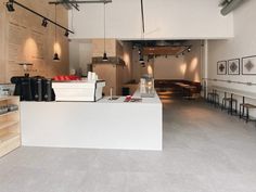 the interior of a restaurant with tables and stools, lights hanging from the ceiling