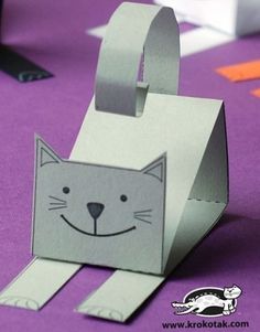 an origami cat is sitting on top of a purple tablecloth and it's made out of paper